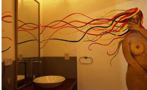 a woman in a bathroom with a painting of a tree at El Pueblito Hotel Boutique in Samaipata +125 photos