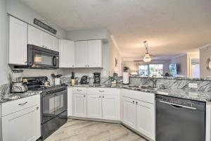 a kitchen with white cabinets and stainless steel appliances at St Pete Condo with Patio and Pool about 2 Mi to Beach in St Petersburg