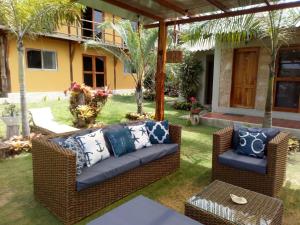 um pátio com mobiliário de vime e palmeiras em Cucube em Ayangue