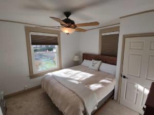 1 dormitorio con 1 cama, ventilador de techo y ventana en Rancher's Capitol Lodge en Cheyenne