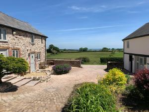 a stone house with a patio and a garden at The Nook at Pentregaer Ucha, with tennis court & lake. in Oswestry
