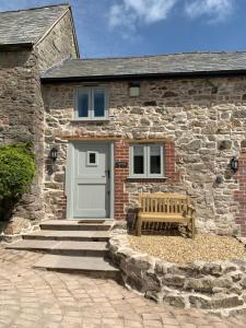 a stone house with a bench in front of it at The Nook at Pentregaer Ucha, with tennis court & lake. in Oswestry