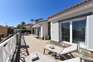 a patio with white chairs and a balcony at Chalet Santa Ana 19 by VillaGranCanaria in Playa del Ingles