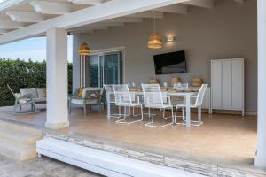 a patio with a table and chairs and a television at VILLA GEMMA MARE E PISCINA RISCALDATA in Santa Maria Del Focallo