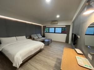 Yawan Hotel في Wenquan: غرفة نوم بسرير واريكة وتلفزيون