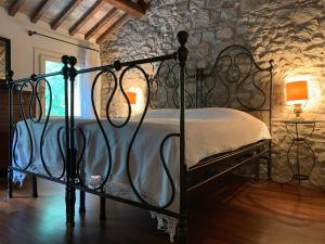 ein Schlafzimmer mit einem Metallbett in einer Steinmauer in der Unterkunft Euganean Hills Natural Park: Casale Il Boschetto in Torreglia