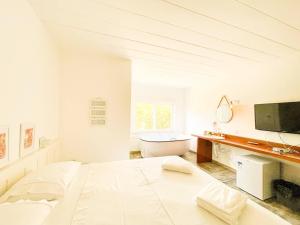 1 dormitorio blanco con 1 cama grande y bañera en Maris Campos do Jordão, en Campos do Jordão
