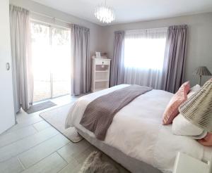 a bedroom with a bed with white sheets and pink pillows at Silverdunes - GardenView in Bettyʼs Bay