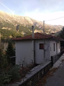 a small white house with a mountain in the background at Aetofolia Melissourgoi in Melissourgoi