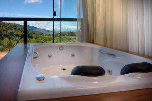 a bath tub with two chairs in front of a window at ÁGUA MARINHA Pousada Caparao in Divisa