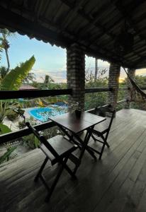 a table and chairs on a wooden deck with a view at Hostel do Ceu in Pipa