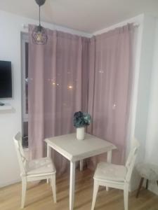 a table with two chairs and a table with a vase on it at Apartman Viktoria in Tuzla