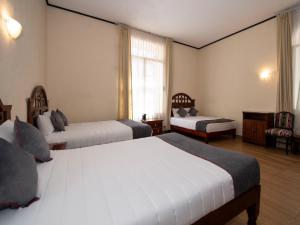 a hotel room with two beds and a window at Hotel Senorial in Querétaro
