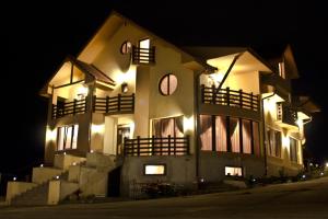 un grand bâtiment avec des lumières allumées la nuit dans l'établissement Pensiunea Neredy, à Baile Unu Mai