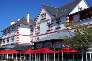 un gran edificio blanco con sombrillas rojas delante en Les Cottages du Limonay, en Saint-Méloir-des-Ondes