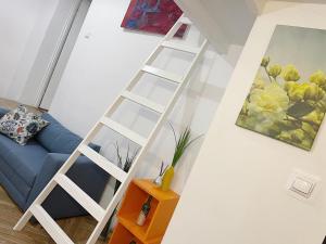 a white ladder in a living room with a couch at Apartamenty Wojewódzka in Katowice