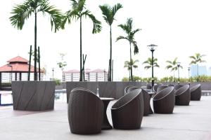 a row of chairs with palm trees in the background at UTM Hotel & Residence in Kuala Lumpur