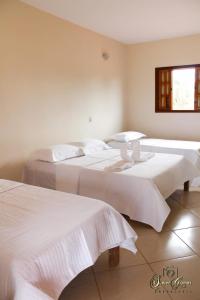 two beds with white sheets in a room at Pousada Esperança in Boa Esperança