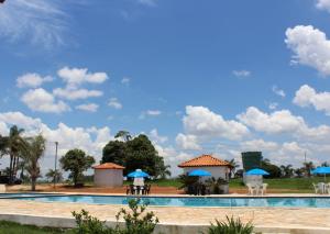 a swimming pool with blue umbrellas and chairs at Pousada Esperança in Boa Esperança