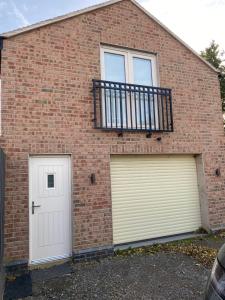a brick building with two garage doors and a balcony at The Apartment Cold Comfort Farm in Hinckley