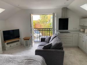 a living room with a couch and a tv and a kitchen at The Apartment Cold Comfort Farm in Hinckley