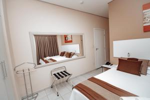 a hotel room with two beds and a mirror at Plaza Dutra Hotel in Caçapava