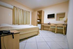 a hotel room with a bed and a desk at Plaza Dutra Hotel in Caçapava