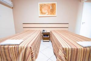 a room with two beds and a table at Plaza Dutra Hotel in Caçapava