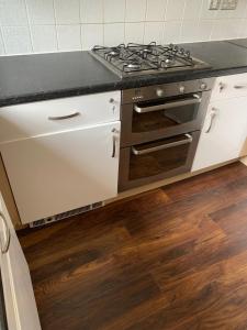 a stove top oven in a kitchen with wooden floors at Private Rooms In A Cheerful 4-Bedroom Town House in Broughton