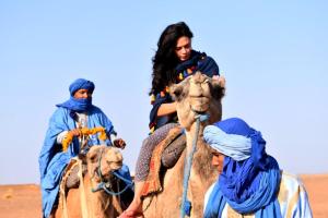 two people riding on the backs of camels in the desert at Tikida Camp by tinfou in Zagora