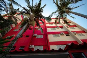 a red building with palm trees in front of it at Plaza Dutra Hotel in Caçapava