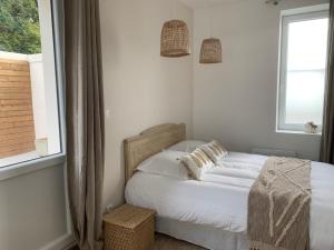 Schlafzimmer mit einem Bett mit weißer Bettwäsche und einem Fenster in der Unterkunft LES JARDINS avec terrasse in Amiens