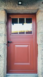 una puerta roja con una ventana en una pared de piedra en Casa João Rodas, en Soajo