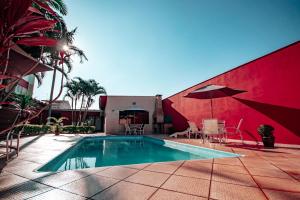 uma piscina com cadeiras e um guarda-sol ao lado de um edifício em Plaza Dutra Hotel em Caçapava