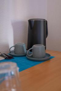 dos tazas en una mesa con una cafetera en Mint Hotel, en Prizren