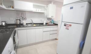 a kitchen with white cabinets and a white refrigerator at Departamentos a Pasos del Mar in Puerto Madryn