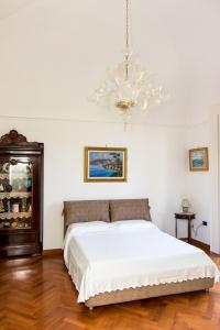 1 dormitorio con cama blanca y lámpara de araña en Capitano Nino Guest House, en Meta