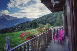 einen rosa Stuhl auf einem Balkon mit Bergblick in der Unterkunft Maison Lucien in Gignod