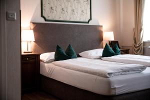 2 Betten in einem Hotelzimmer mit grünen Kissen in der Unterkunft Boutique-Hotel Amalienhof in Weimar
