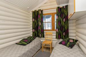 two beds in a room with a chair and a window at Hallan Akka Apartments in Hyrynsalmi