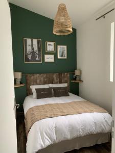 een slaapkamer met een groot bed met een groene muur bij LES GRENOUILLES in Amiens