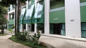 a green and white building with trees in front of it at Apart hotel Champagnat in Belo Horizonte