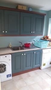 uma cozinha com armários azuis, um lavatório e uma máquina de lavar louça em Everest Lodge Guest House em Dunfanaghy