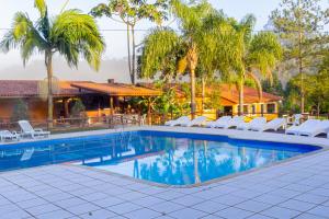 a swimming pool with lounge chairs and a house at Pousada Bezerra in Nazaré Paulista