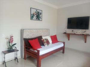 a living room with a bench with red and white pillows at Casa nova com piscina próxima a praia e menos de 3km do centro de Ubatuba in Ubatuba