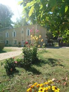 a building with a bunch of flowers in the yard at Location meublée au milieu d'un écrin de verdure Aux vieux fours in Noaillac