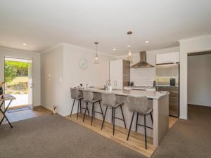 a kitchen with a large island with bar stools at Pauanui Pines - Pauanui Holiday Home in Pauanui