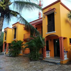 une maison jaune avec un palmier devant elle dans l'établissement Hacienda Valentina, à Playa del Carmen