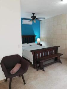 a bedroom with a bed and a couch and a chair at Hacienda Valentina in Playa del Carmen