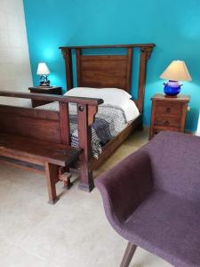 a bedroom with a bed with a bench and a chair at Hacienda Valentina in Playa del Carmen